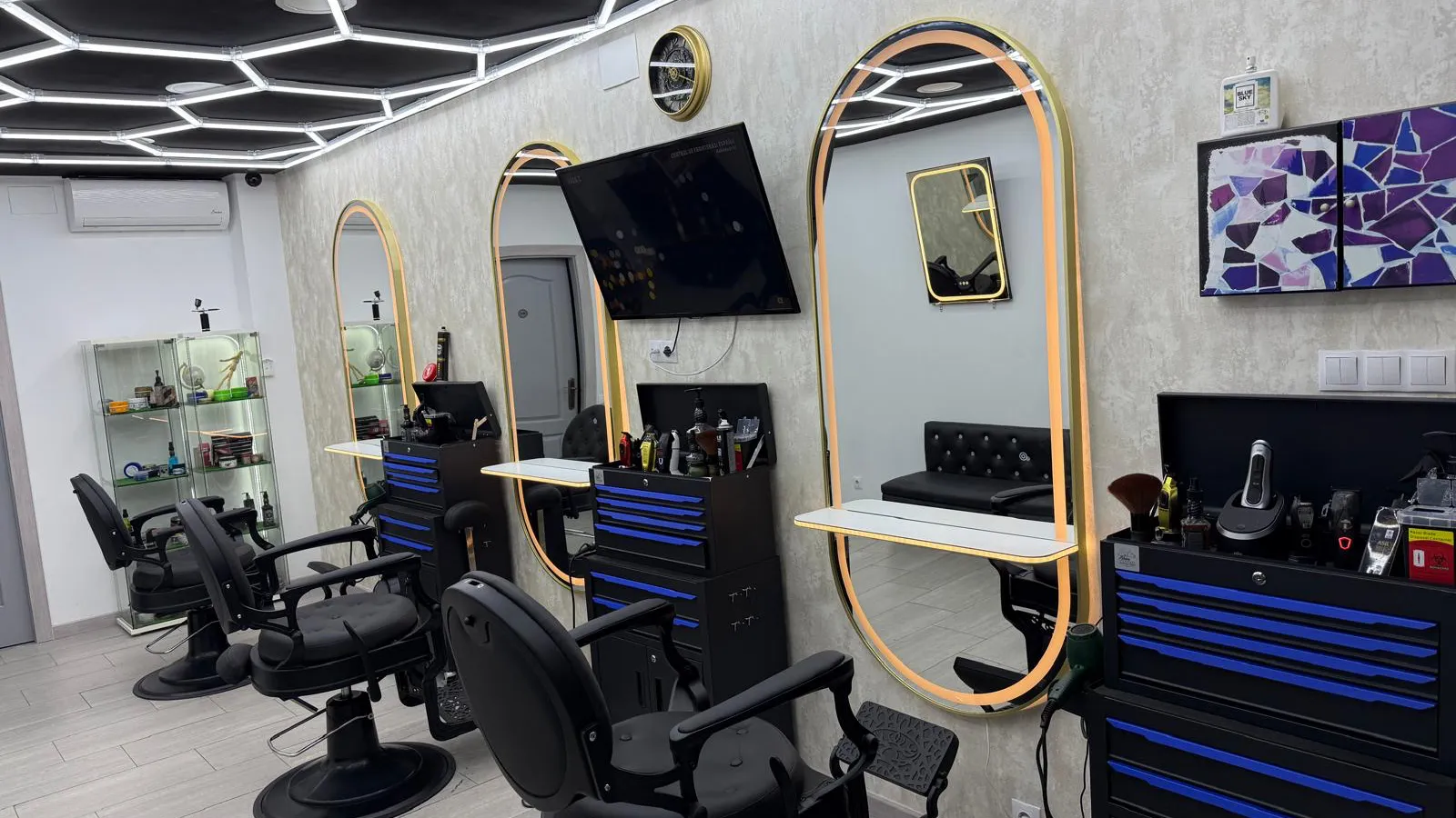 Interior: tres puestos con espejos ovalados de marco dorado, sillones negros y techo de luces en hexágono
